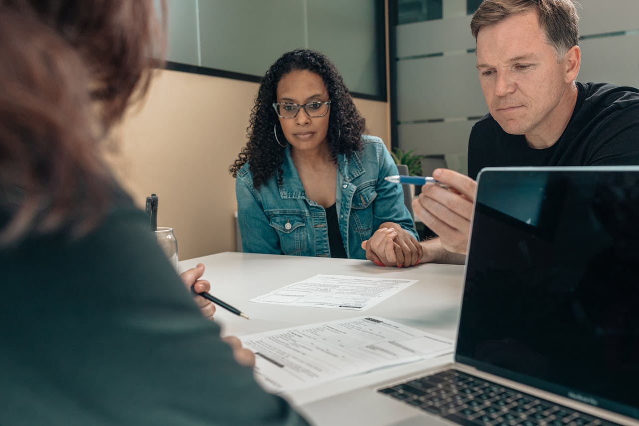services-01 A couple reviewing documents with a professional in an office setting, focusing on financial planning.