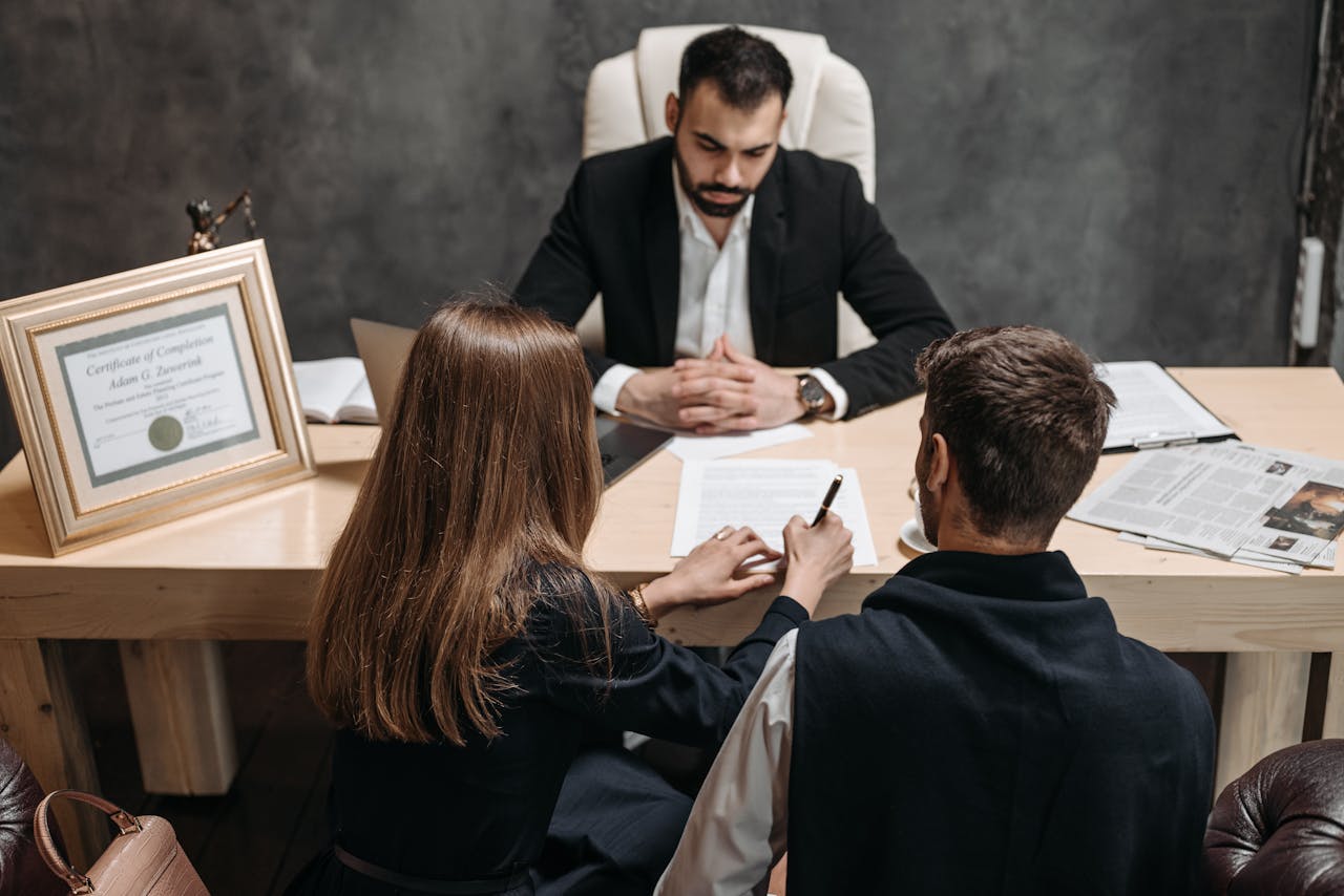 services-02 A lawyer discusses legal documents with clients in an office setting.